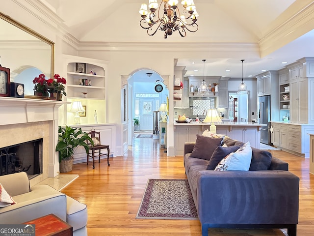 living room featuring lofted ceiling, a high end fireplace, a chandelier, and light hardwood / wood-style flooring