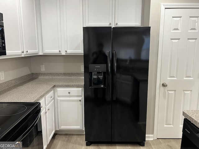 kitchen with black appliances, white cabinets, and light hardwood / wood-style flooring