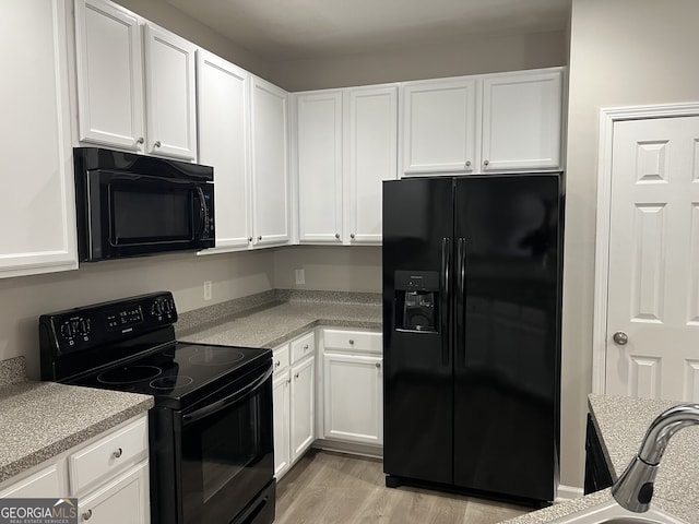 kitchen with light hardwood / wood-style floors, white cabinetry, and black appliances