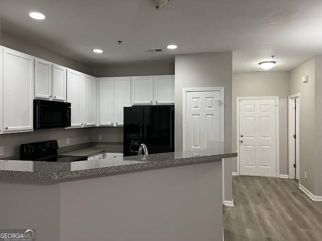 kitchen with kitchen peninsula, light hardwood / wood-style flooring, white cabinetry, and black appliances