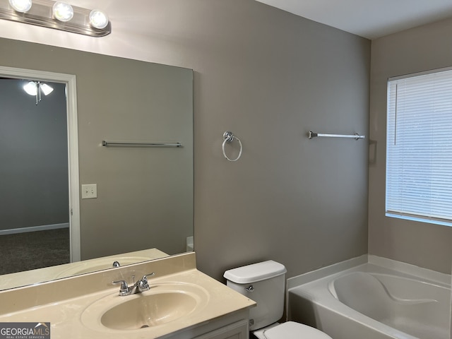 bathroom featuring a washtub, vanity, and toilet