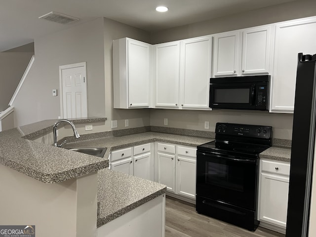 kitchen with kitchen peninsula, sink, white cabinets, and black appliances