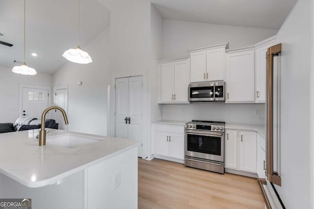 kitchen featuring white cabinets, appliances with stainless steel finishes, lofted ceiling, and sink