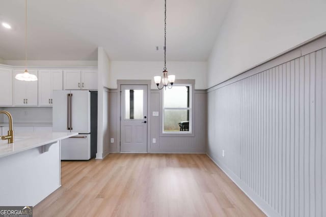 kitchen with white cabinets, high end white fridge, light hardwood / wood-style floors, and pendant lighting