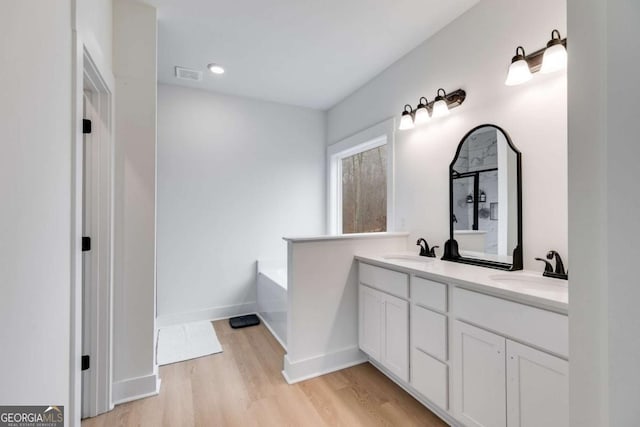 bathroom featuring a bath, wood-type flooring, and vanity