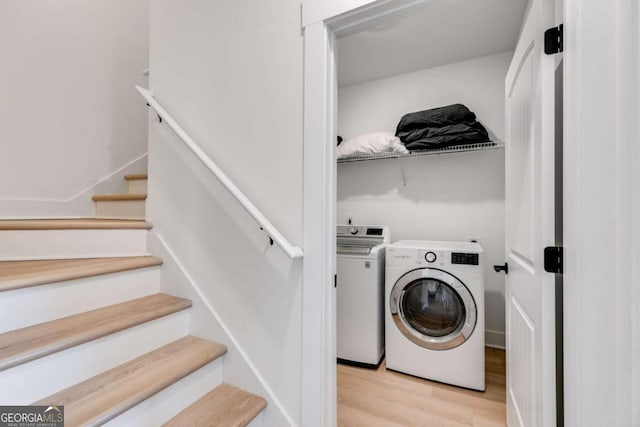 laundry area with independent washer and dryer and light hardwood / wood-style flooring