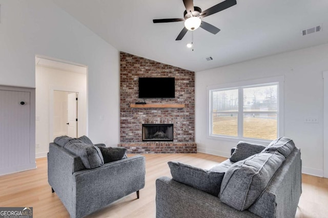 living room featuring a fireplace, light wood-type flooring, ceiling fan, and lofted ceiling