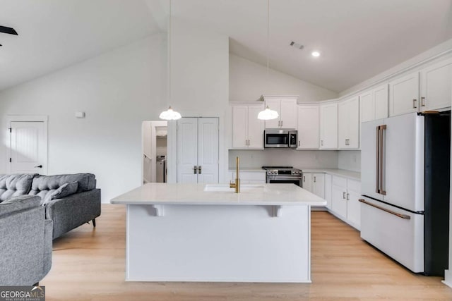 kitchen with light wood-type flooring, stainless steel appliances, a center island with sink, high vaulted ceiling, and white cabinets