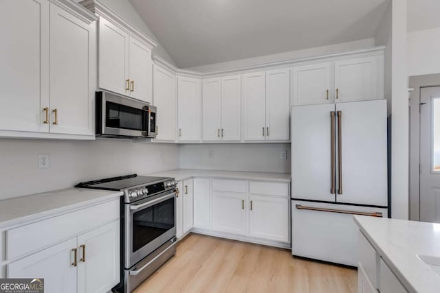 kitchen with white cabinetry, stainless steel appliances, vaulted ceiling, and light wood-type flooring