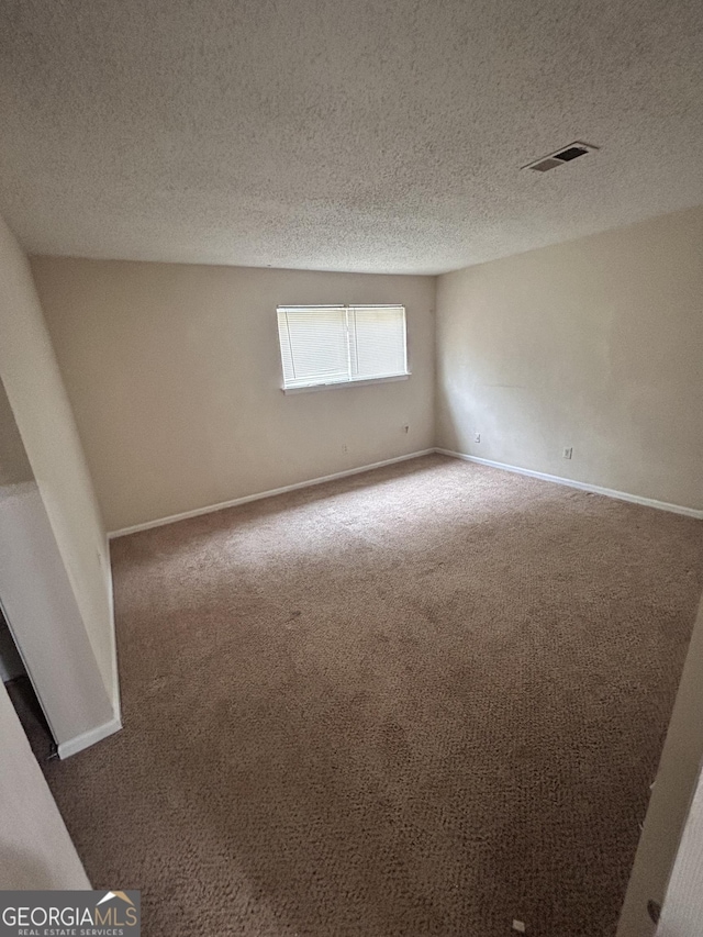 empty room with a textured ceiling and carpet floors