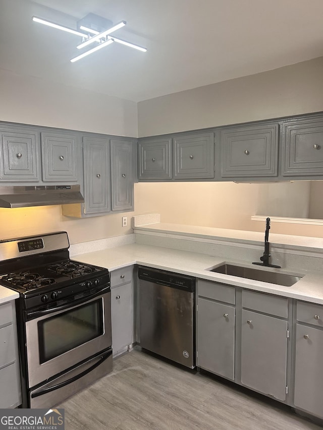 kitchen featuring gray cabinetry, sink, stainless steel appliances, and light wood-type flooring