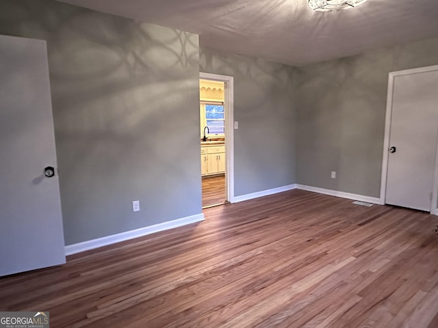 unfurnished room with hardwood / wood-style floors and sink