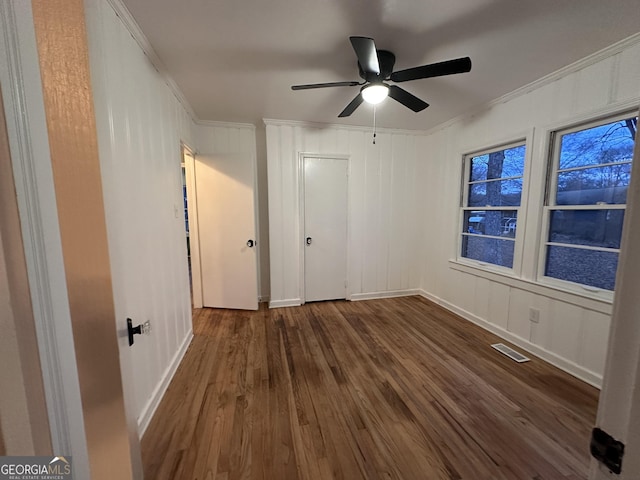 unfurnished bedroom with ceiling fan, dark hardwood / wood-style flooring, and ornamental molding