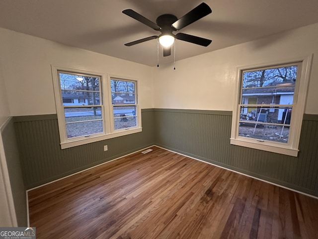 spare room with hardwood / wood-style floors, ceiling fan, and wood walls