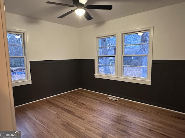 unfurnished room featuring ceiling fan, wood walls, and wood-type flooring