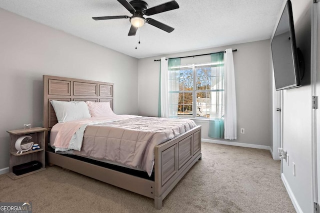 bedroom with a textured ceiling, light colored carpet, and ceiling fan