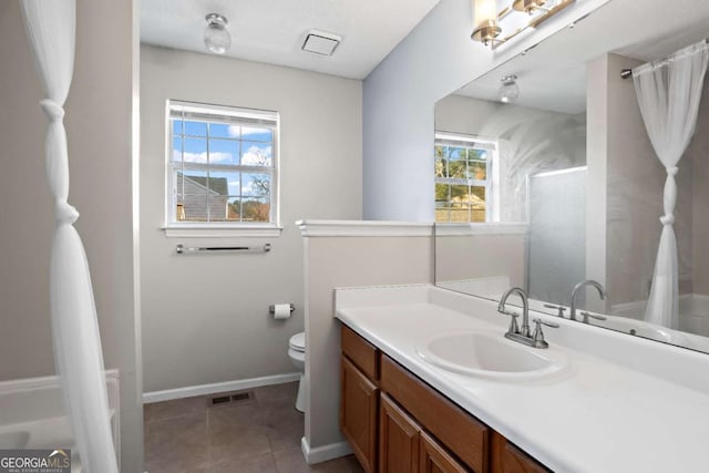 bathroom with tile patterned flooring, vanity, toilet, and a wealth of natural light