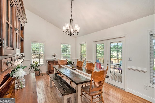 dining space with french doors, high vaulted ceiling, light hardwood / wood-style floors, and a notable chandelier