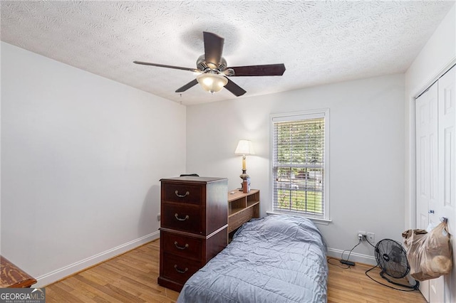 bedroom featuring ceiling fan, a closet, a textured ceiling, and light hardwood / wood-style flooring