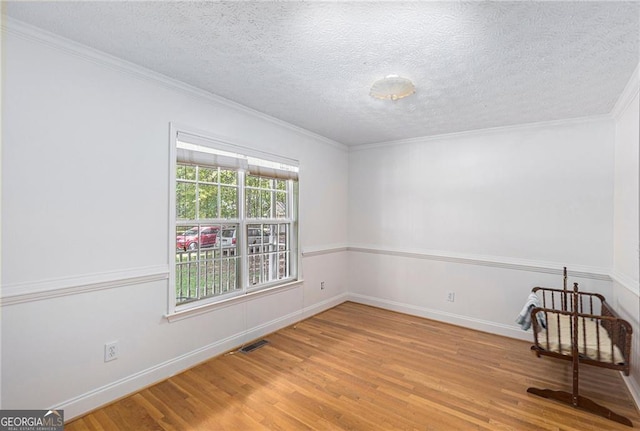 empty room featuring hardwood / wood-style floors, crown molding, and a textured ceiling