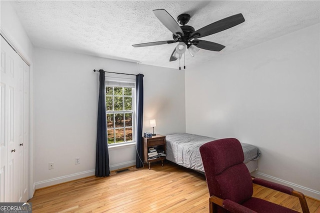 bedroom featuring ceiling fan, wood-type flooring, a textured ceiling, and a closet