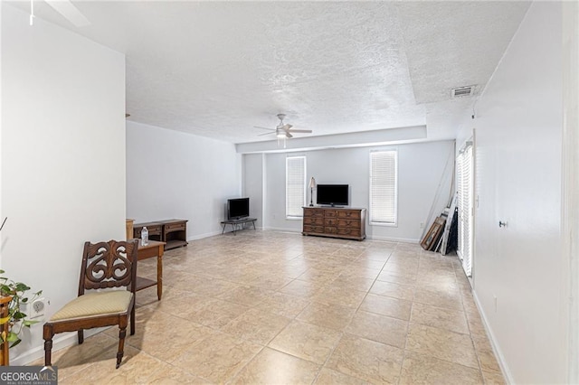 living room featuring ceiling fan and a textured ceiling