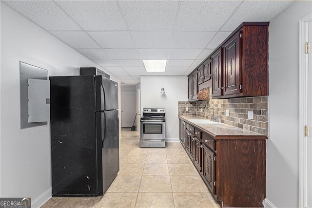 kitchen featuring a paneled ceiling, backsplash, stainless steel range with electric cooktop, black fridge, and sink