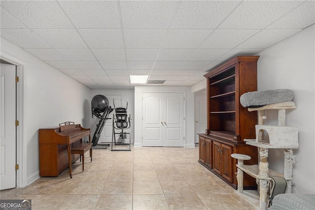 interior space featuring a paneled ceiling and light tile patterned floors