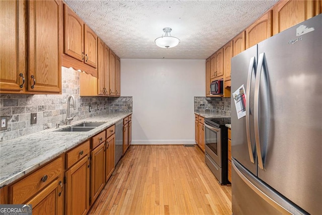 kitchen featuring decorative backsplash, light hardwood / wood-style floors, sink, and stainless steel appliances