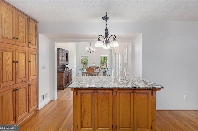 kitchen featuring a chandelier, a kitchen island, and light hardwood / wood-style flooring