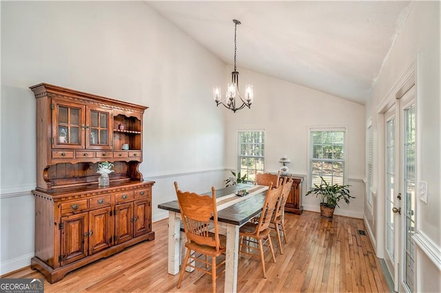 dining space with high vaulted ceiling, a chandelier, and light wood-type flooring