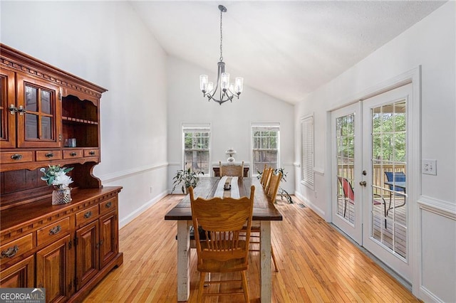 dining space featuring french doors, high vaulted ceiling, an inviting chandelier, and light hardwood / wood-style flooring