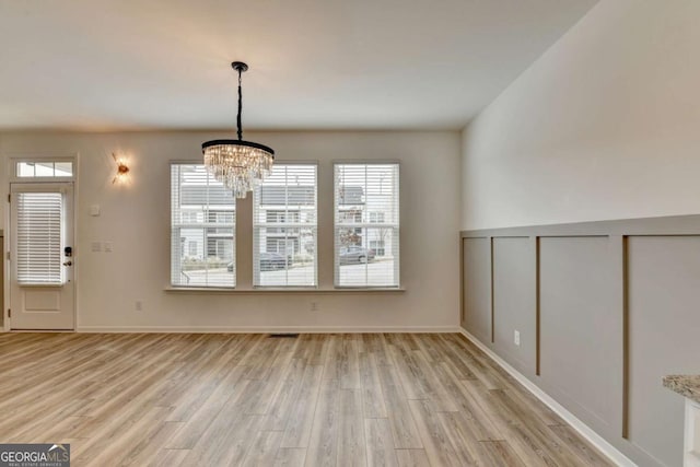 unfurnished dining area with light hardwood / wood-style flooring and a chandelier