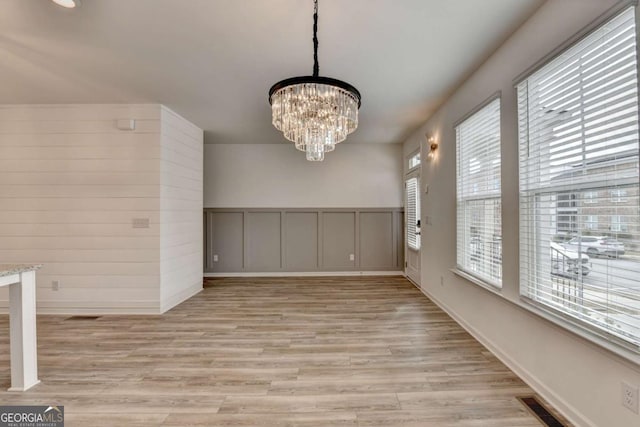 unfurnished dining area featuring light hardwood / wood-style flooring and a notable chandelier