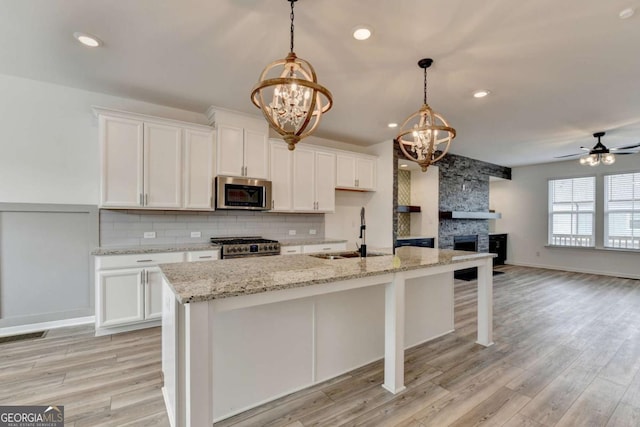 kitchen featuring white cabinets, appliances with stainless steel finishes, a center island with sink, and sink