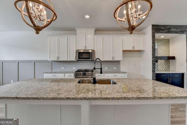 kitchen with white cabinets, an inviting chandelier, hanging light fixtures, and appliances with stainless steel finishes