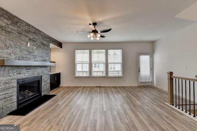 unfurnished living room with ceiling fan, light hardwood / wood-style floors, and a fireplace