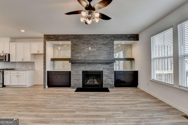 unfurnished living room featuring a fireplace, light wood-type flooring, and ceiling fan