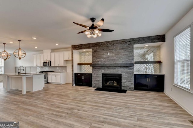 unfurnished living room featuring a fireplace, light wood-type flooring, plenty of natural light, and sink