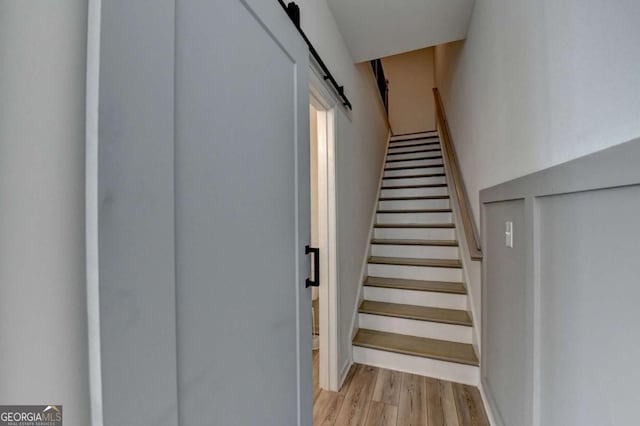 staircase with a barn door and wood-type flooring