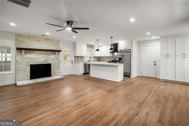 unfurnished living room with a fireplace, light hardwood / wood-style flooring, and ceiling fan