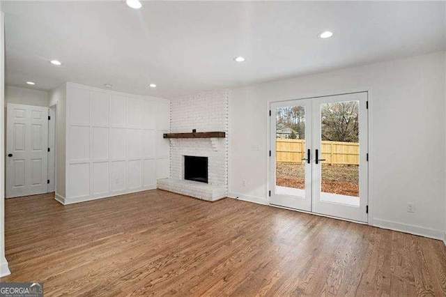 unfurnished living room with a fireplace, french doors, and wood-type flooring