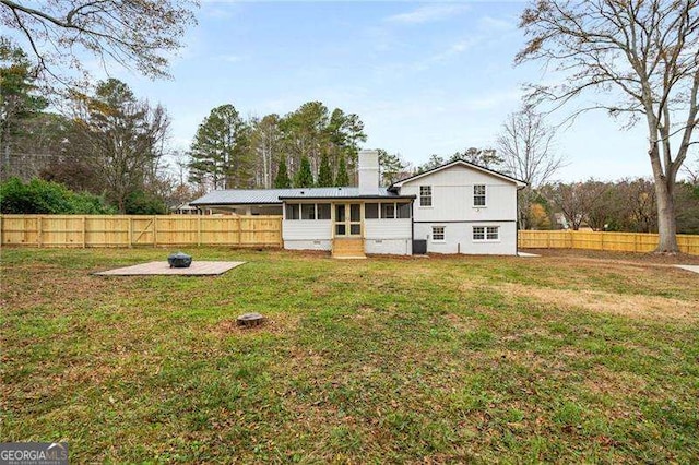 back of house with a fire pit, a lawn, and a sunroom