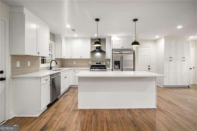 kitchen featuring white cabinets, hardwood / wood-style flooring, a kitchen island, and appliances with stainless steel finishes