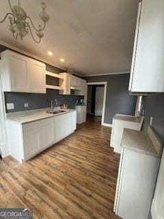 kitchen with white cabinetry, sink, light hardwood / wood-style floors, and ornamental molding