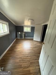 unfurnished living room with lofted ceiling, a wealth of natural light, and dark wood-type flooring