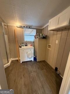 clothes washing area with hookup for a washing machine, dark wood-type flooring, and wooden walls