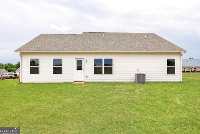 rear view of house with cooling unit and a yard