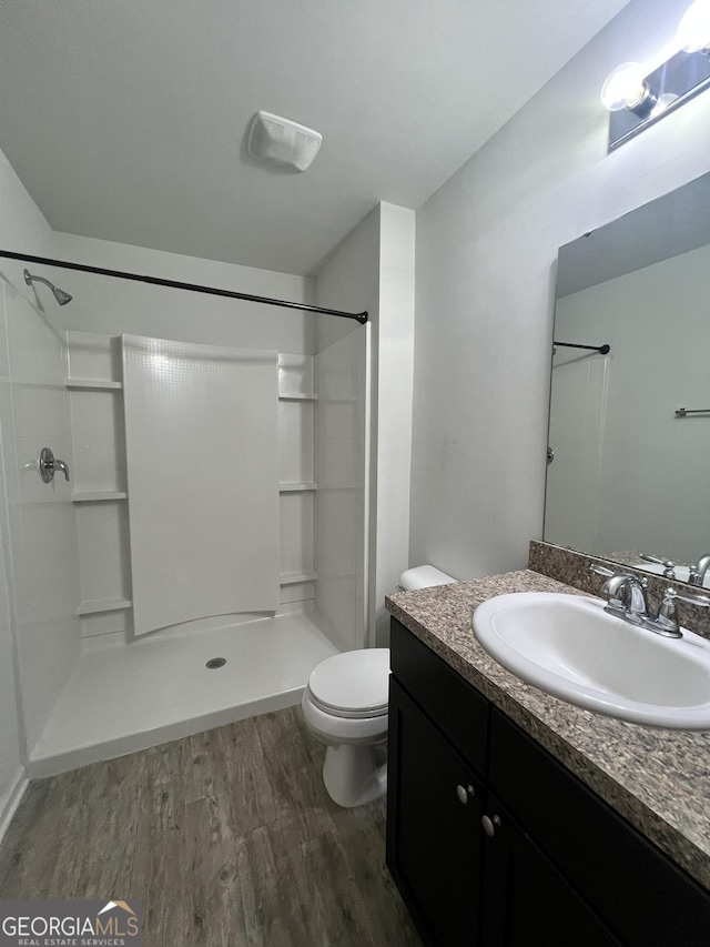 bathroom with walk in shower, vanity, wood-type flooring, and toilet