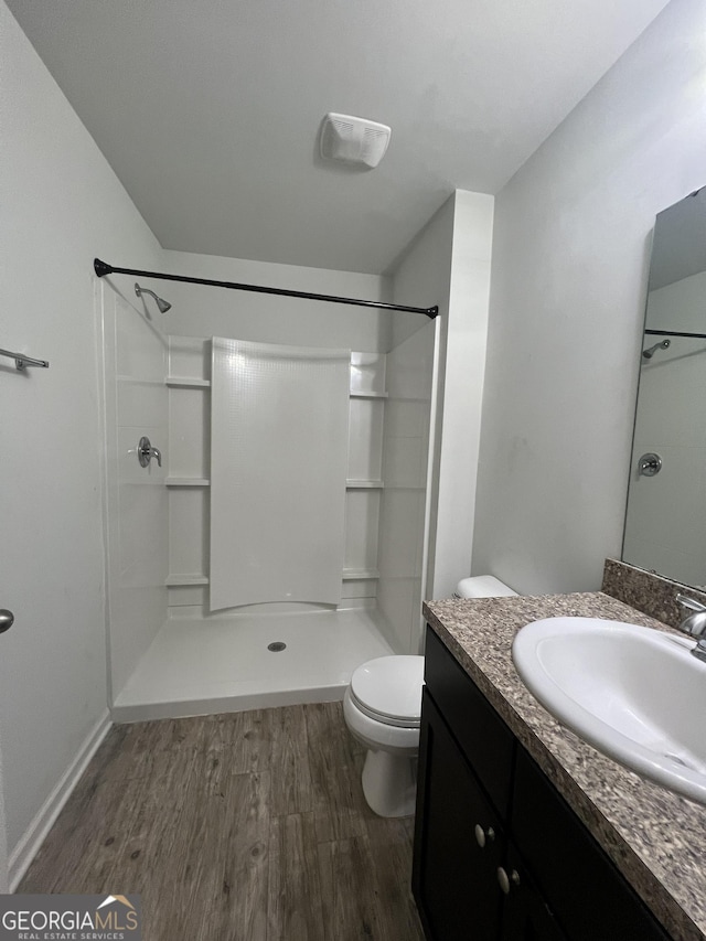 bathroom with a shower, hardwood / wood-style floors, vanity, and toilet